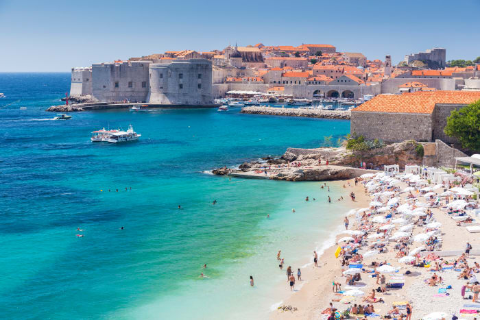 On the beach in Dubrovnik, tourists bath in the warm seas of the Adriatic in Dubrovnik, Croatia.